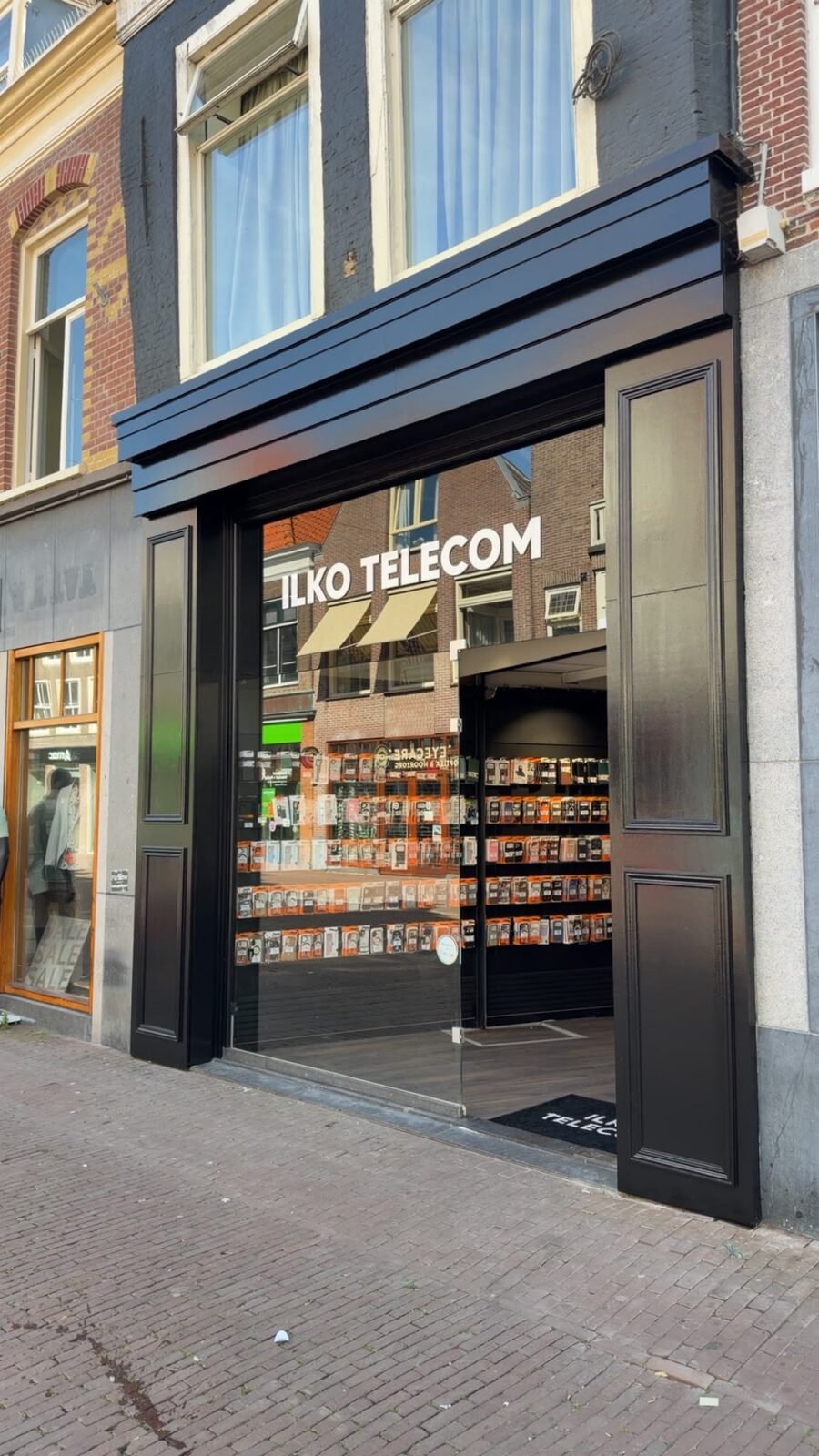 Ilko Telecom gezien vanaf de Grote Noord, met de zwarte pui en de winkelstraat ernaast.